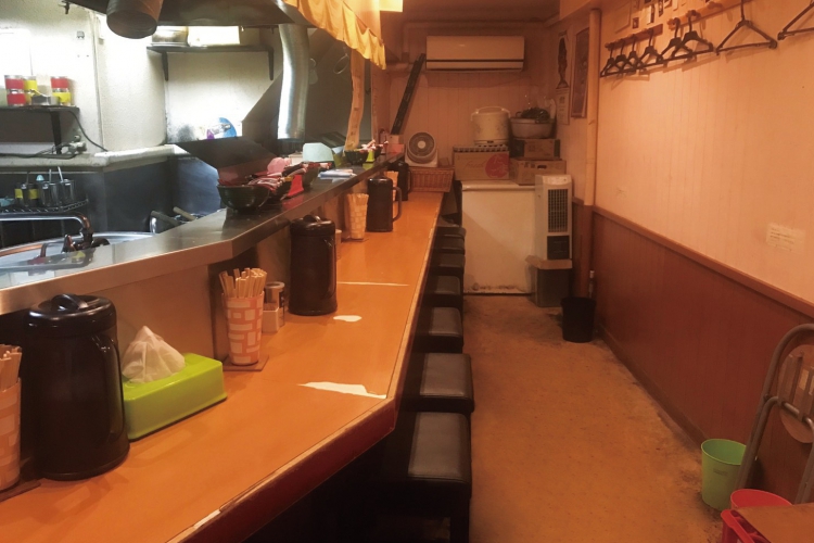 著名人の写真が並ぶ店内は、カウンター9席。食券制での注文 